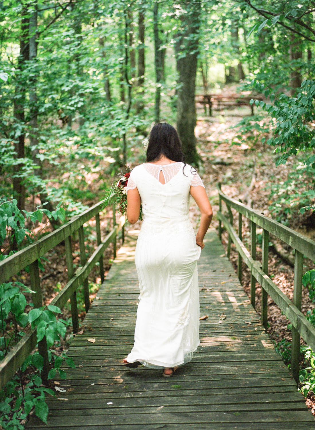 bride in beaded gown walking on bridge in the woods, St. Louis fine art wedding photography