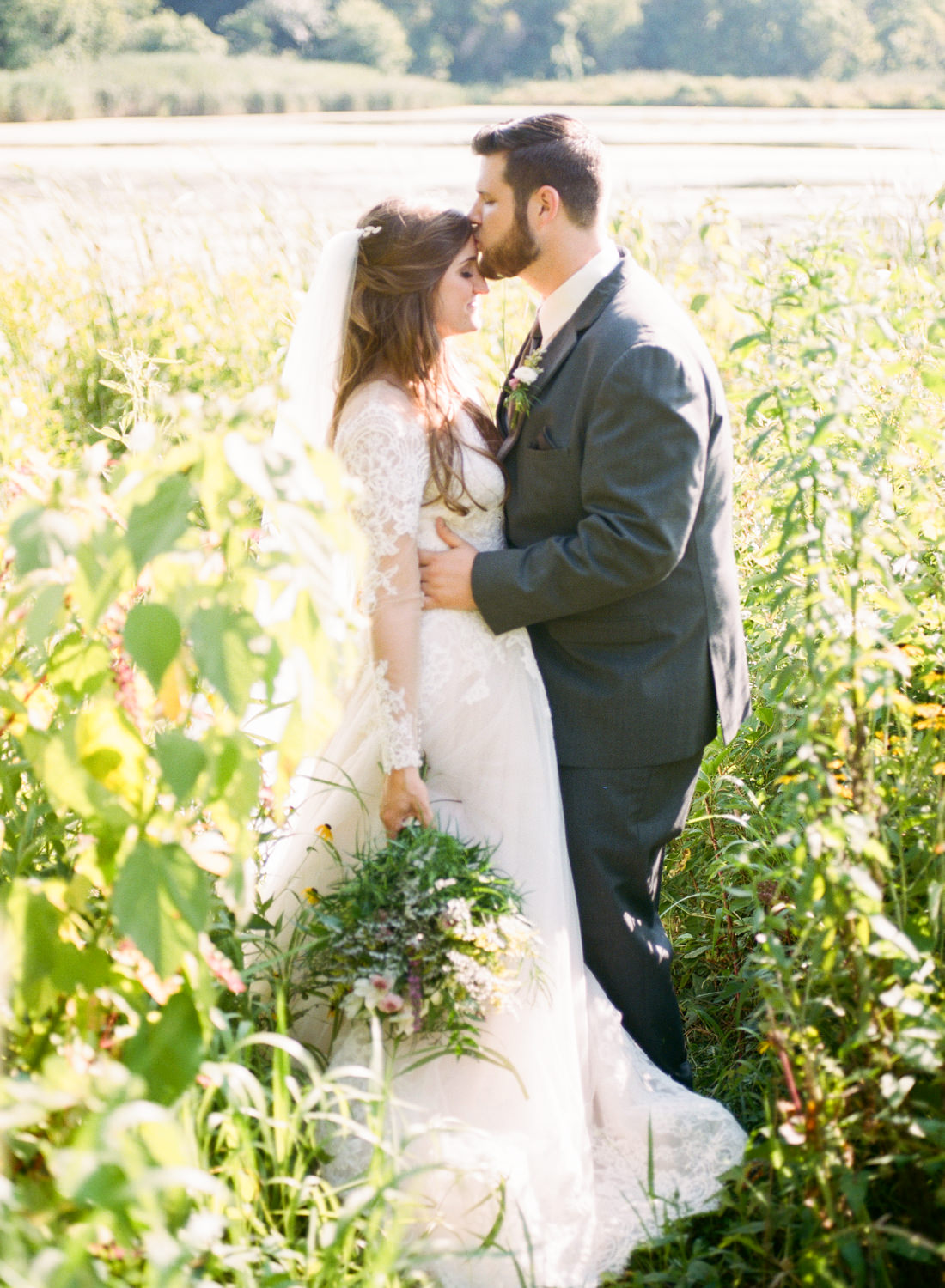Groom kissing bride in field; St. Louis fine art film wedding photographer Erica Robnett Photography