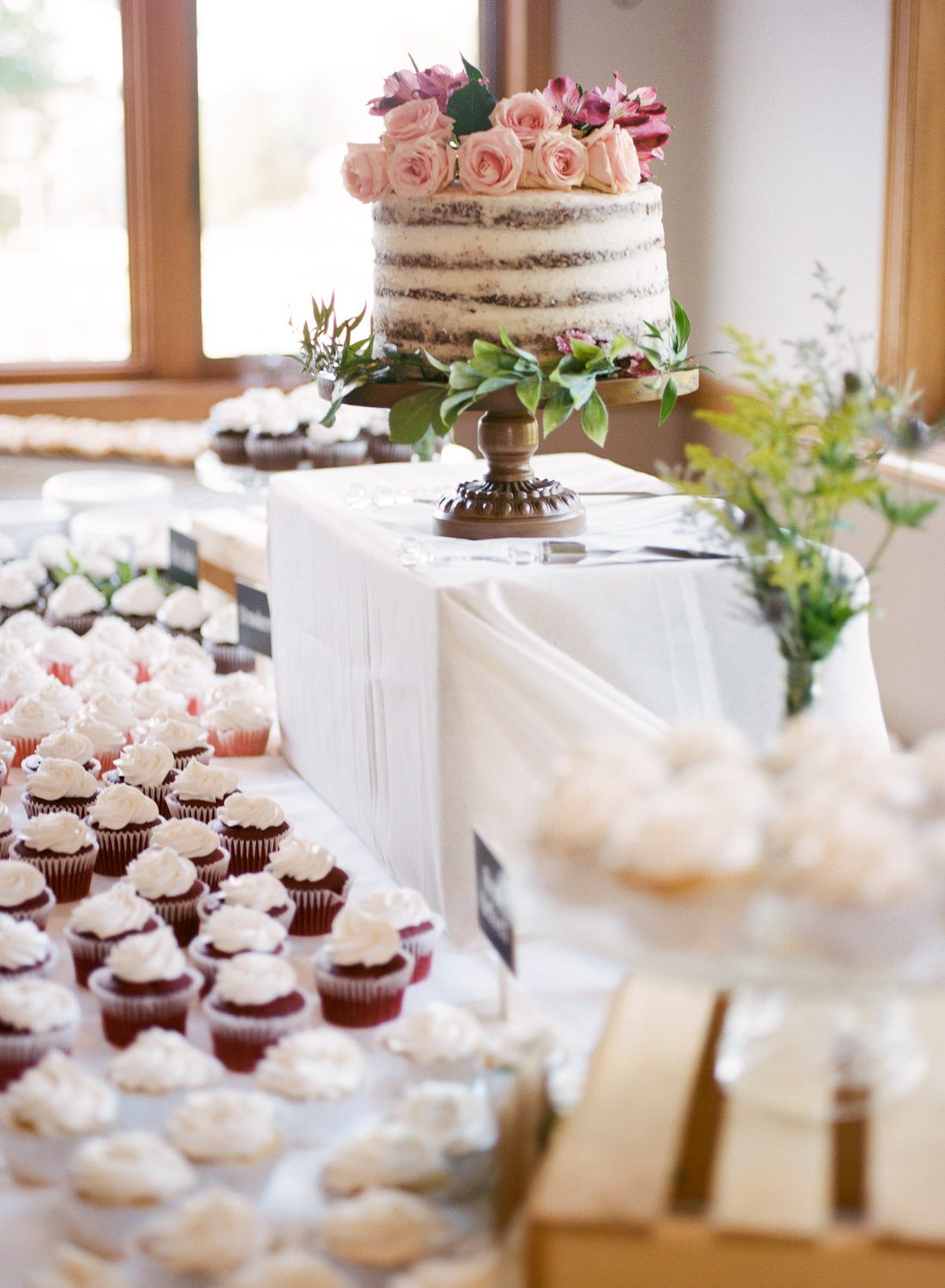 Wedding cake and cupcakes with greenery and pink roses; St. Louis wedding photographer
