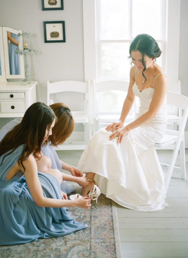 Bridesmaids putting on brides shoes at Defiance Ridge Vineyards; St. Louis fine art film wedding photographer Erica Robnett Photography