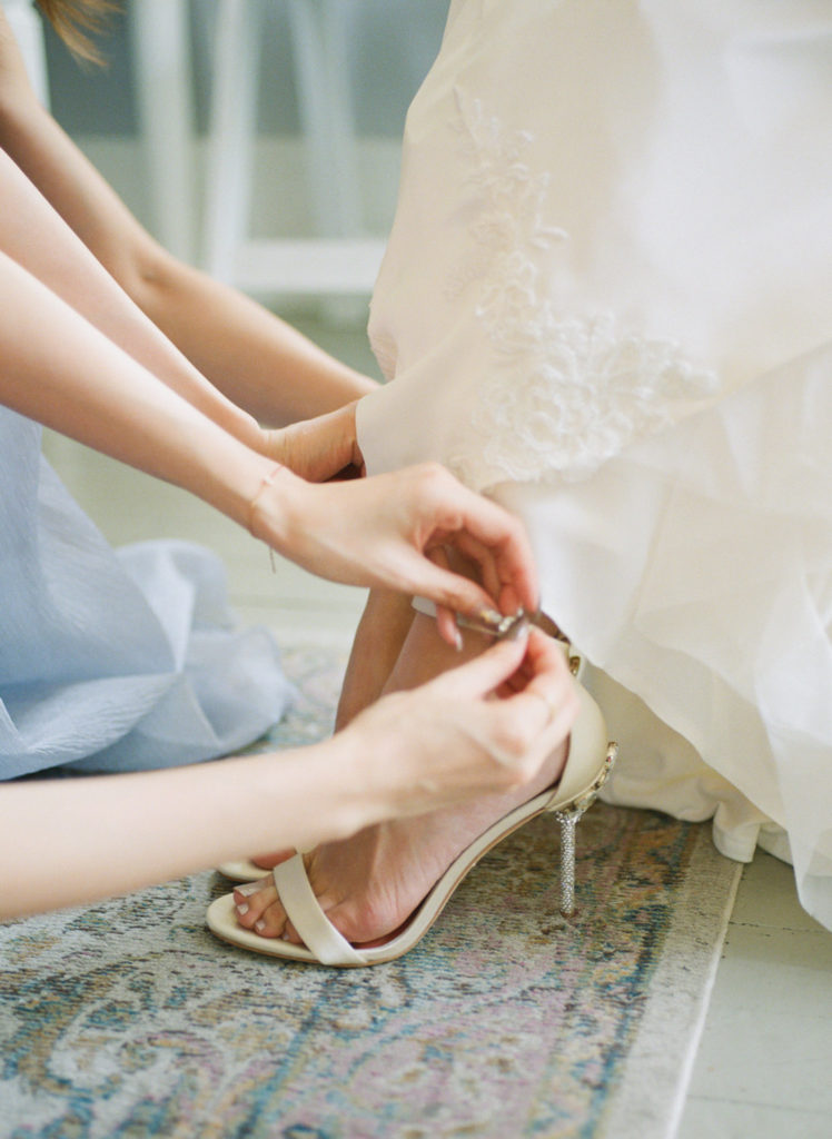Bridesmaids putting on brides shoes at Defiance Ridge Vineyards; St. Louis fine art film wedding photographer Erica Robnett Photography