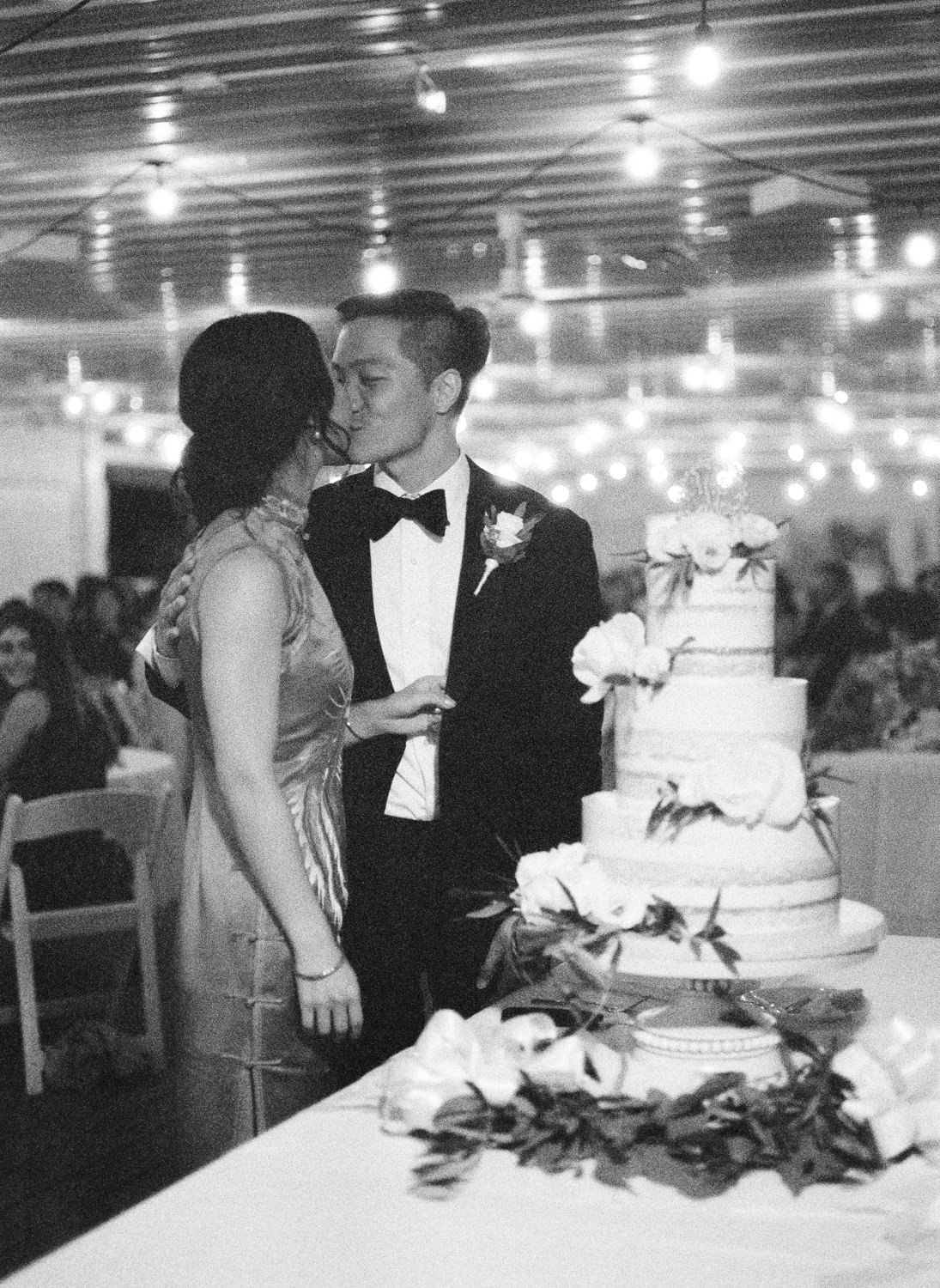 Grainy black and white film photo of bride and groom cutting cake at Defiance Ridge Vineyards