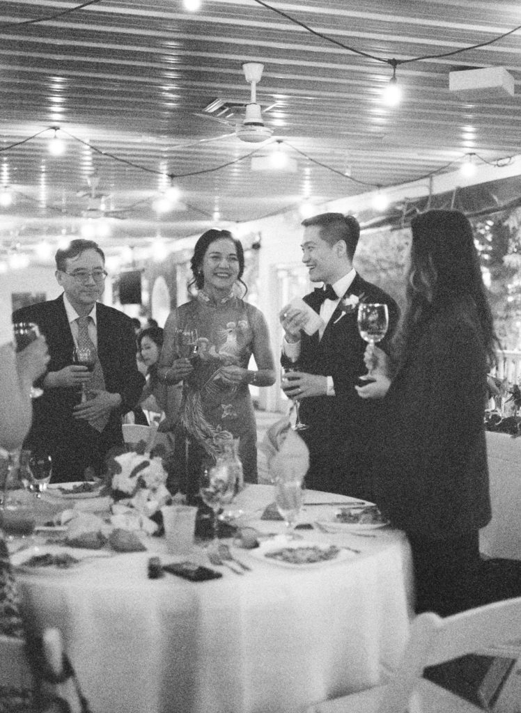 Grainy black and white film photo of bride and groom with guests at Defiance Ridge Vineyards