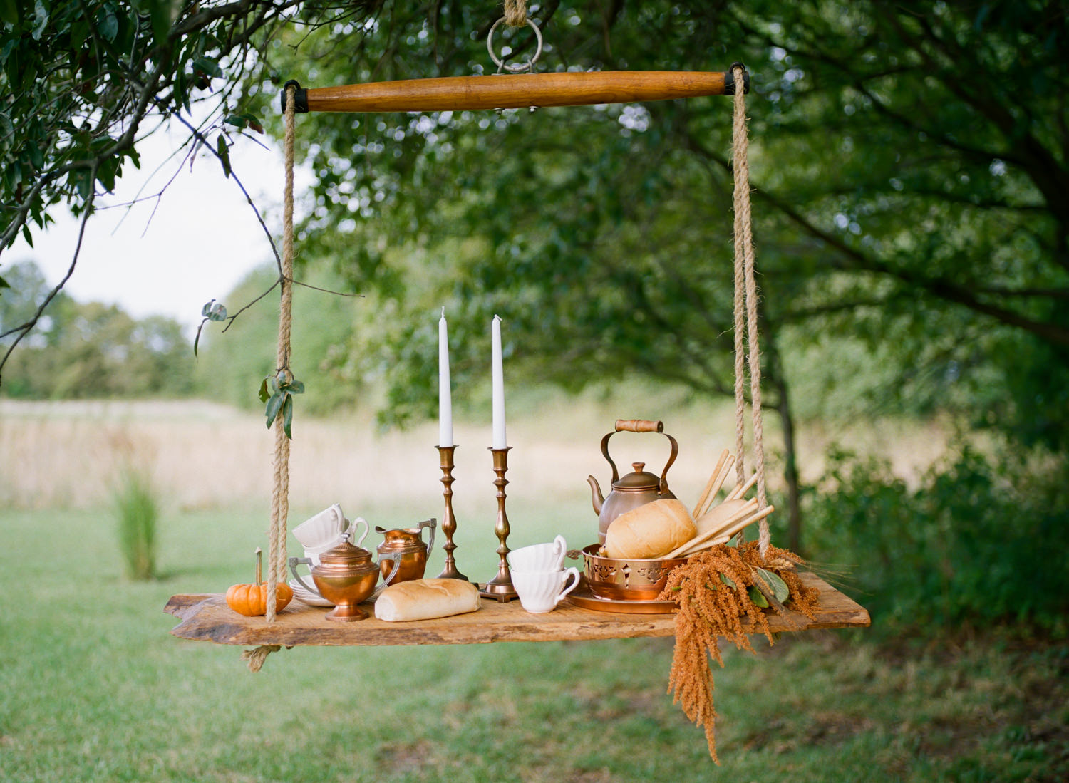 Copper serving dishes, bread loaf, white china, white taper candles on wooden swing shelf, Thanksgiving table at Emerson Fields; St. Louis fine art film wedding photographer Erica Robnett Photography