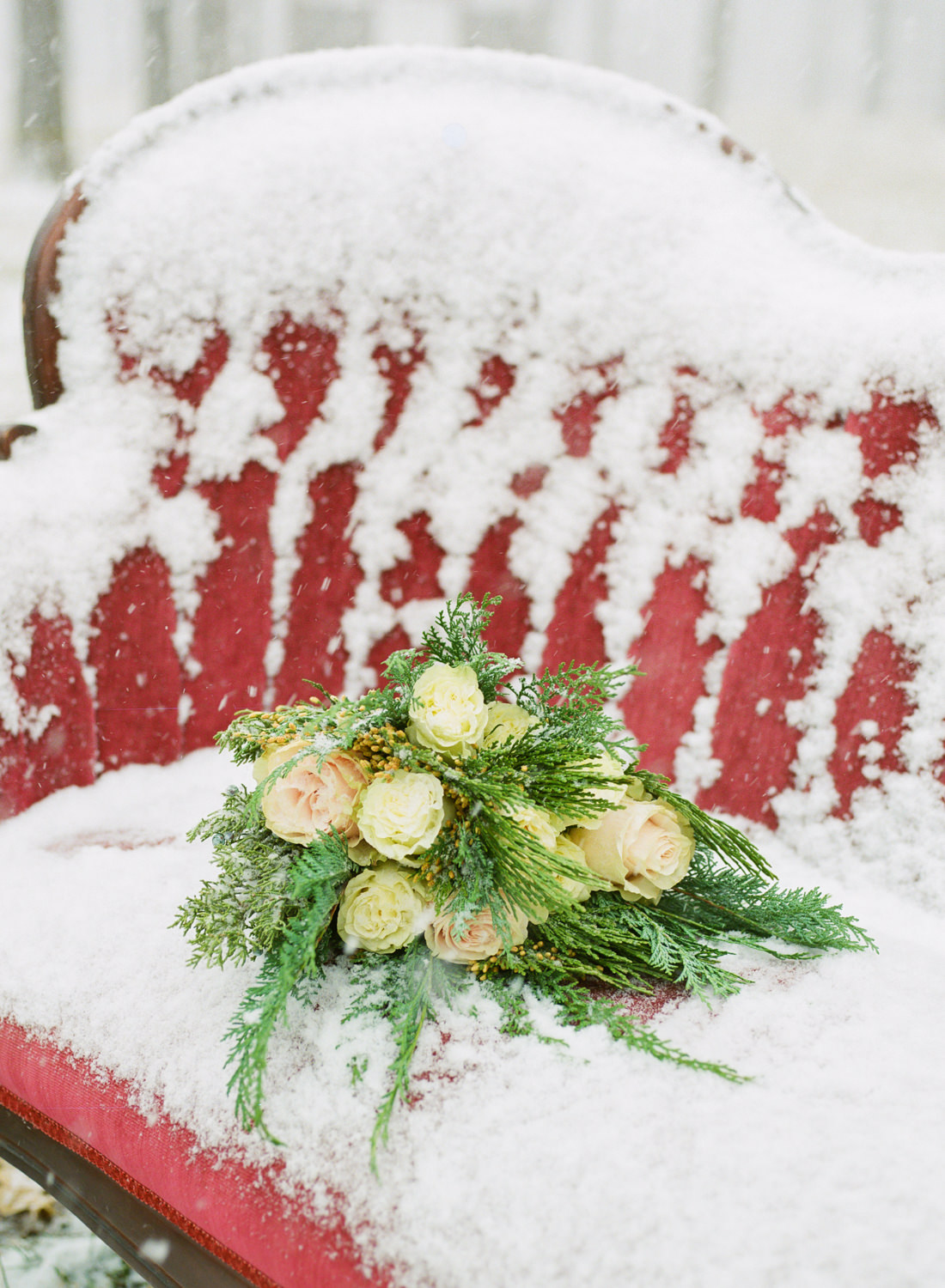 Winter wedding, Red couch and rose and spruce bridal bouquet in snow; St. Louis fine art film wedding photographer Erica Robnett Photography