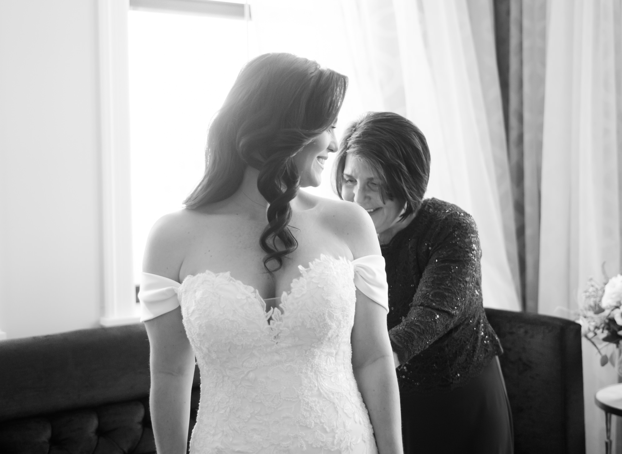 Mother of the bride helping bride into her wedding gown