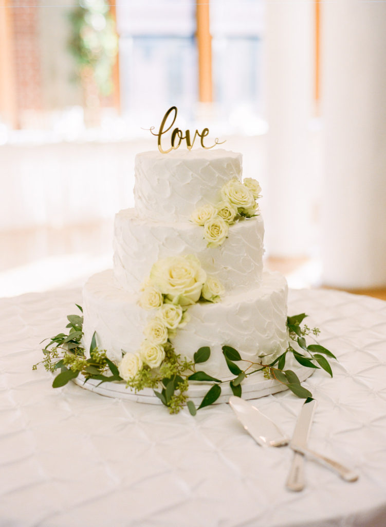 White wedding cake with white flowers and greenery; St. Louis wedding photographer