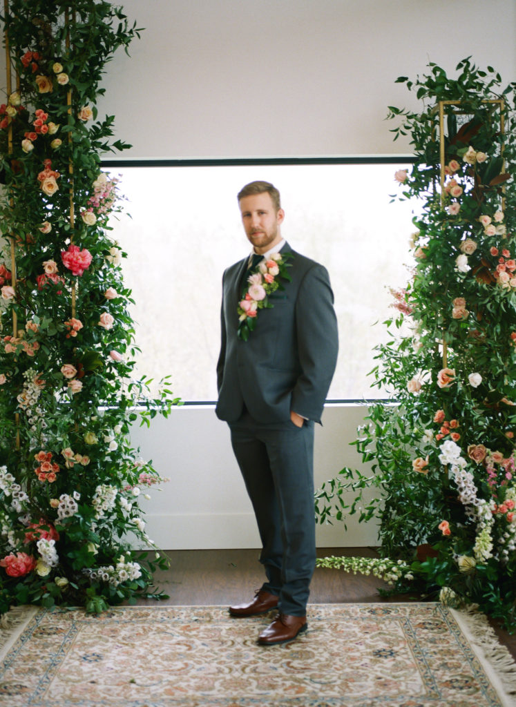 Groom portrait in front of floral ceremony backdrop; St. Louis wedding photographer